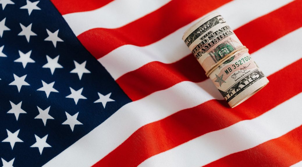 american flag with rolled dollar bills